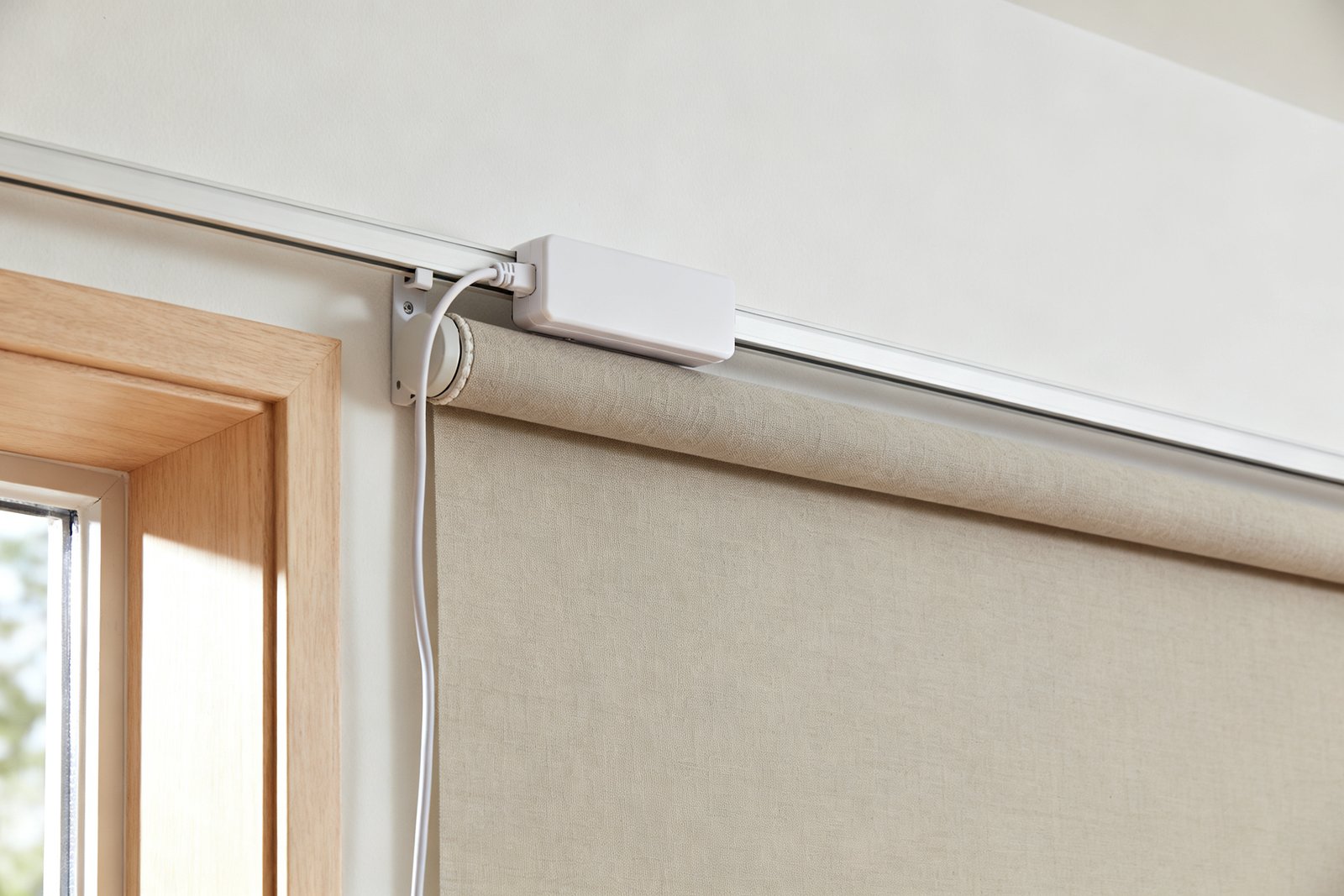 Head rail of a motorized roller shade with a plain battery pack and charging cable, no chain or cord on the shade