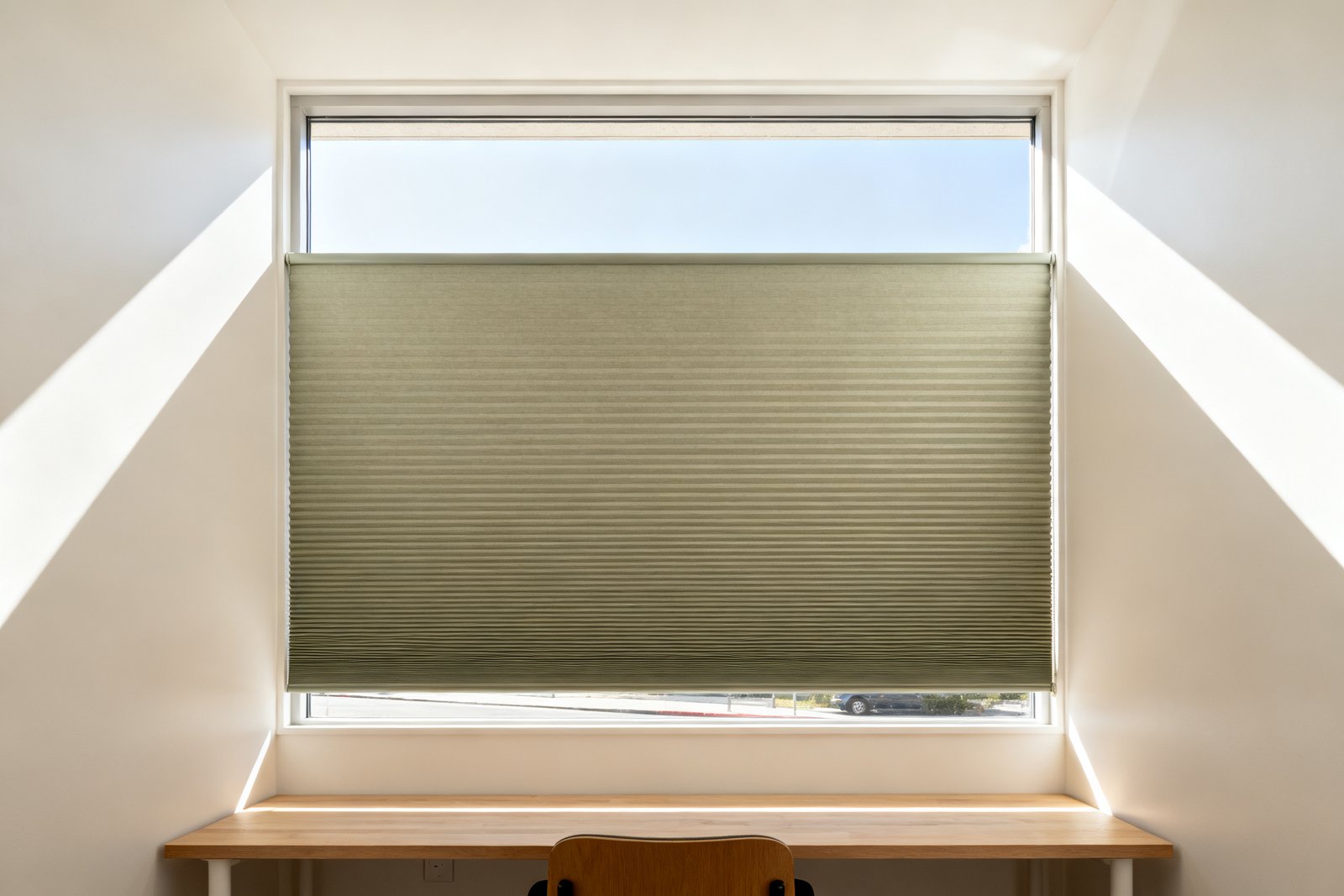 A cellular shade lowered from the top, covering the lower glass for privacy while an open band of bright sky shows across the top.